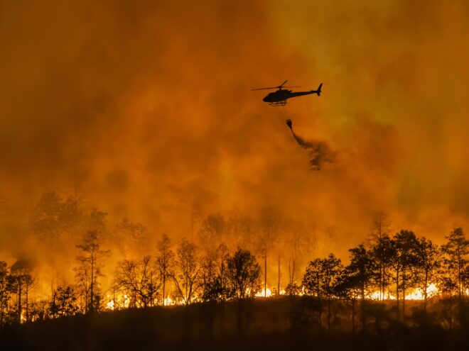 Fire fighting helicopter carry water bucket to extinguish the forest fire shutterstock 2422917965