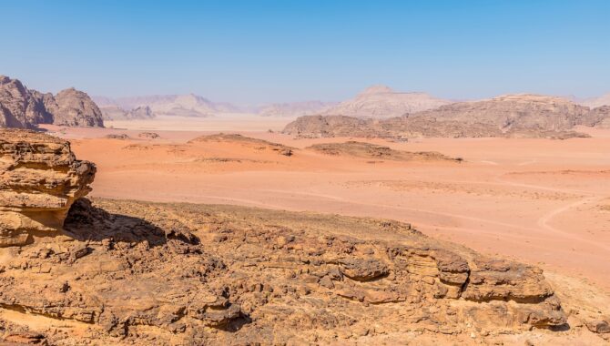 A view past rocky outcrops in the vast desert landscape in Wadi Rum Jordan in summertime shutterstock 2226567629